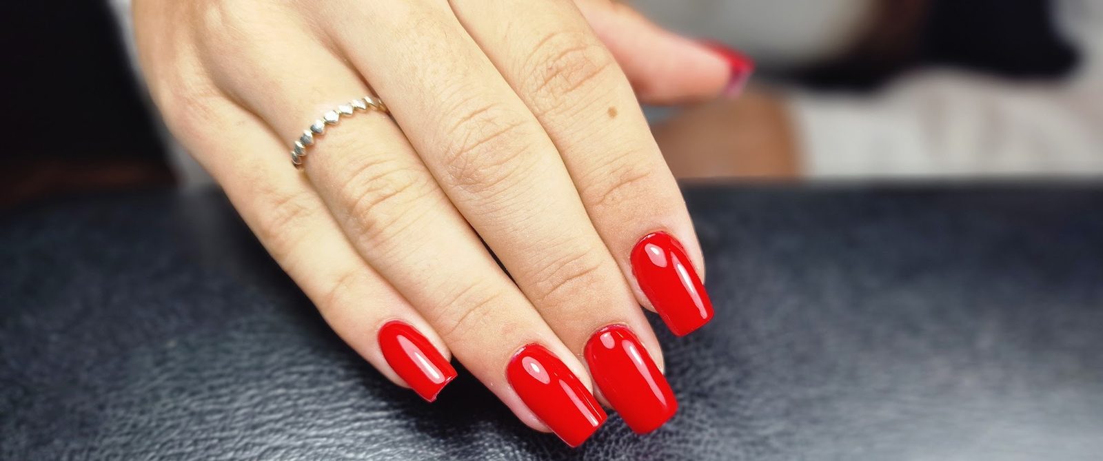Glanzend rode vierkante nagels op zwart leer